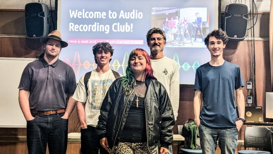 Five members of the audio club in a theater setting.