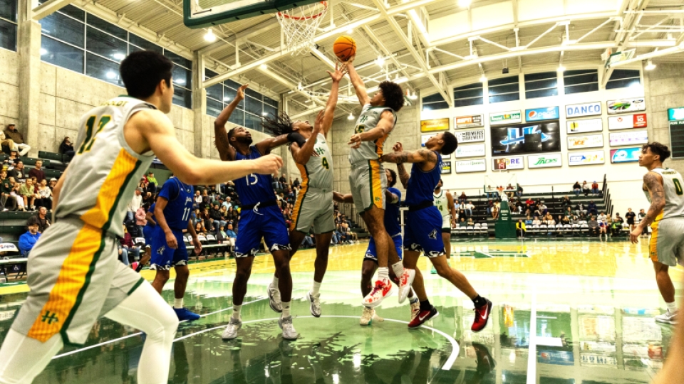 Two basketball teams competing for a lay up/rebound from the basket view.