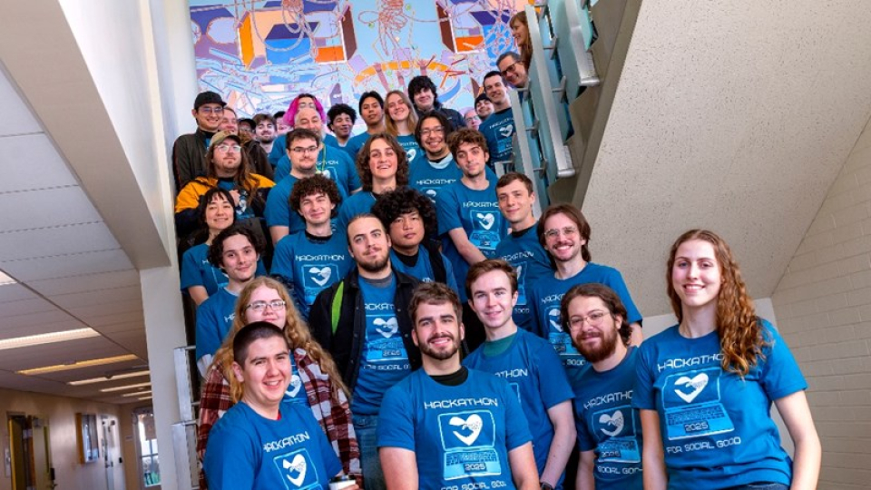 A large group of computer science club members in blue shirts on a staircase.