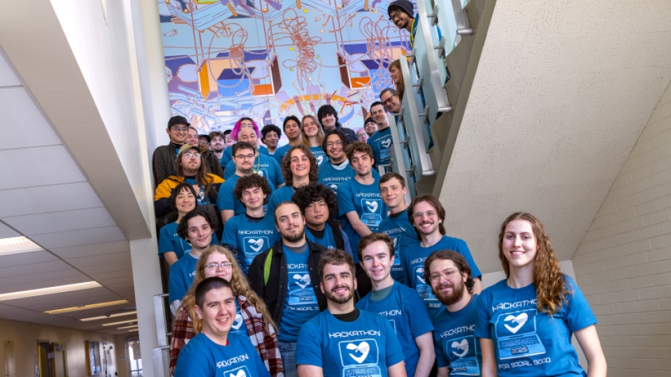 Computer Science club members in blue shirts posing as a group on stairs.