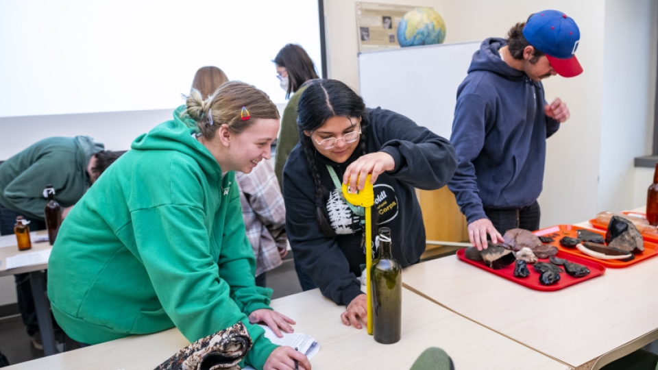 Three students in the Cultural Resources Facility with artifacts.
