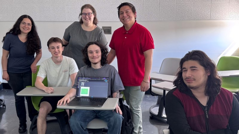 Six data science club members sitting at a desk and standing in a classroom.