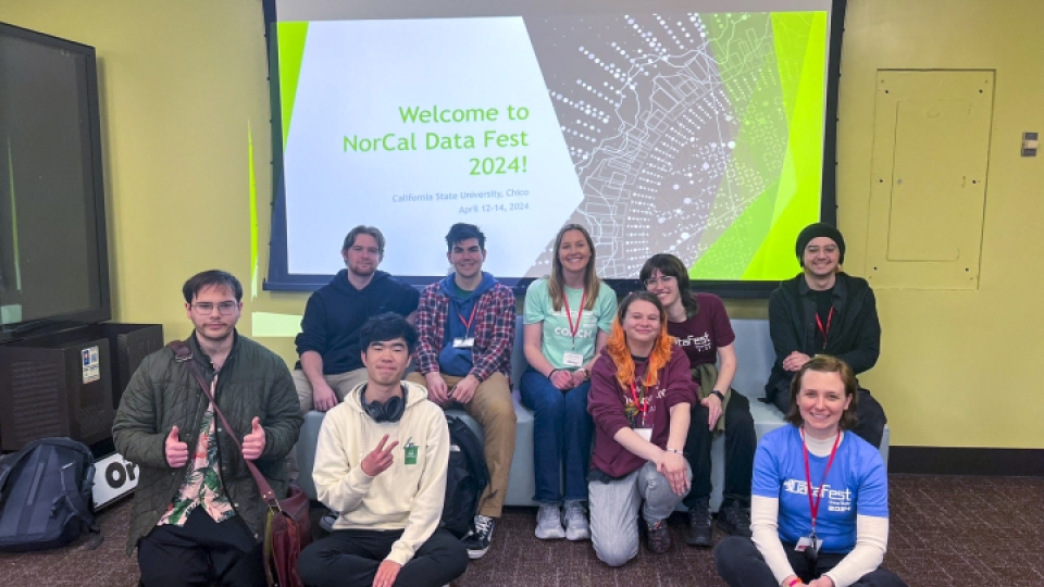 A group of data science students in front of a screen for NorCal Data Fest. 