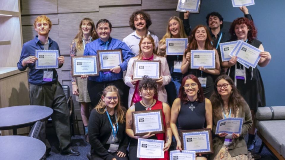 A group photo of journalism students smiling and holding certificates.