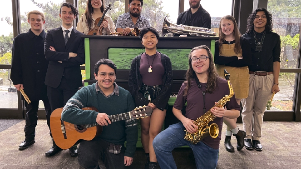 A group of musicians smiling in the music building lobby.
