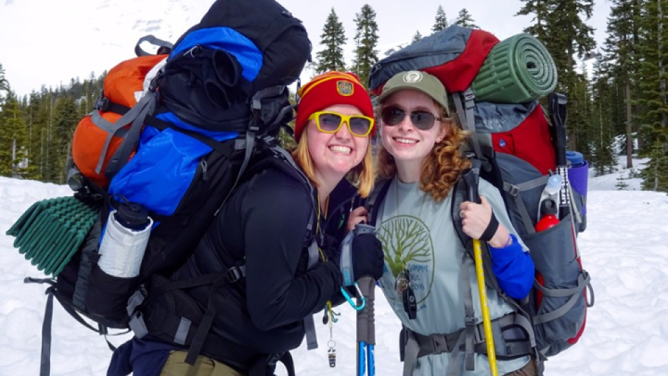 Two smiling outdoor recreation students smiling in their snow backpacking gear.