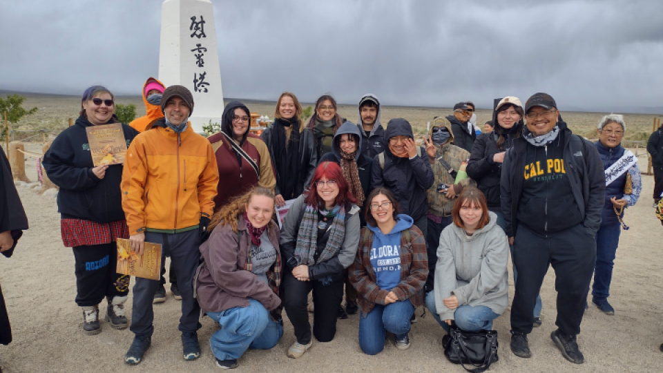 A group of sociology students posing together on a trip with a small monument in the background.
