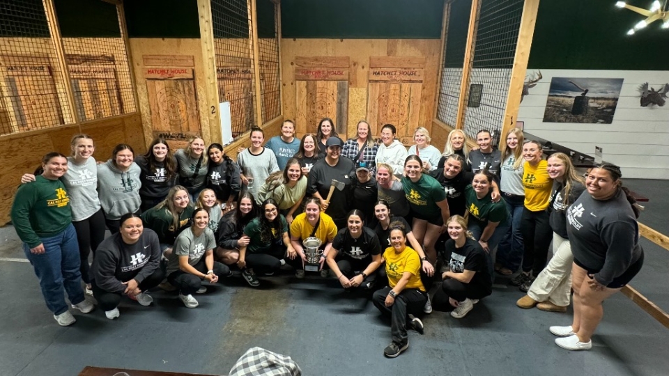 The women's softball team smiling group pic at the Hatchet House. 