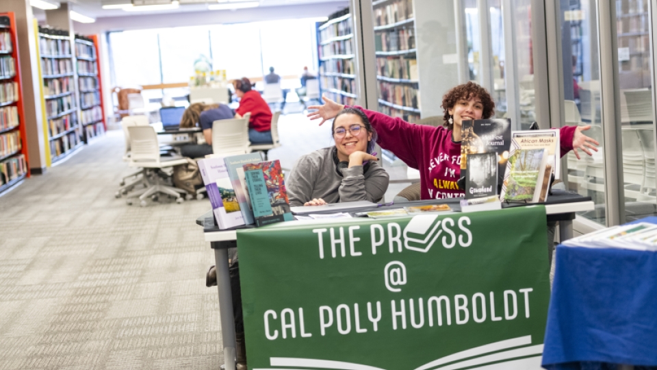 Two students behind a table with information about the Student Publishing Press.