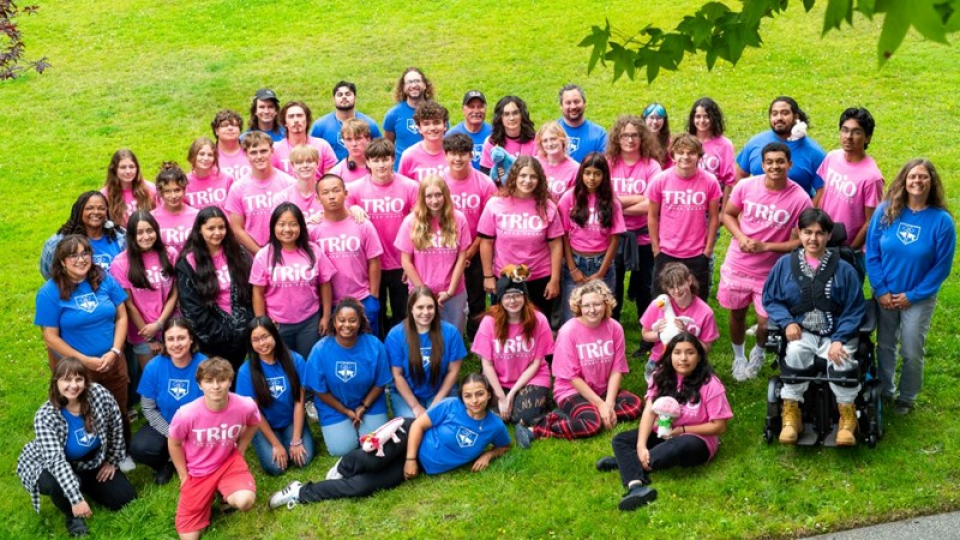 A large group of TRIO members in pink or blue TRIO shirts. 