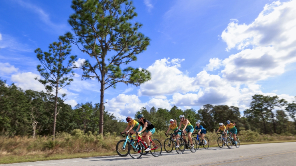Seven women's triathlon athletes riding their bikes.