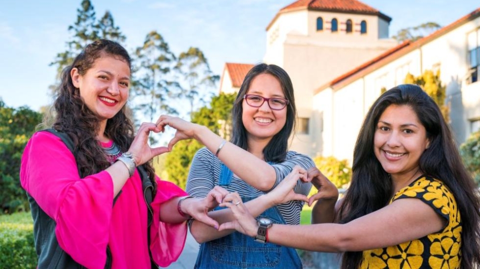 Students smiling and making hearts with their hands.