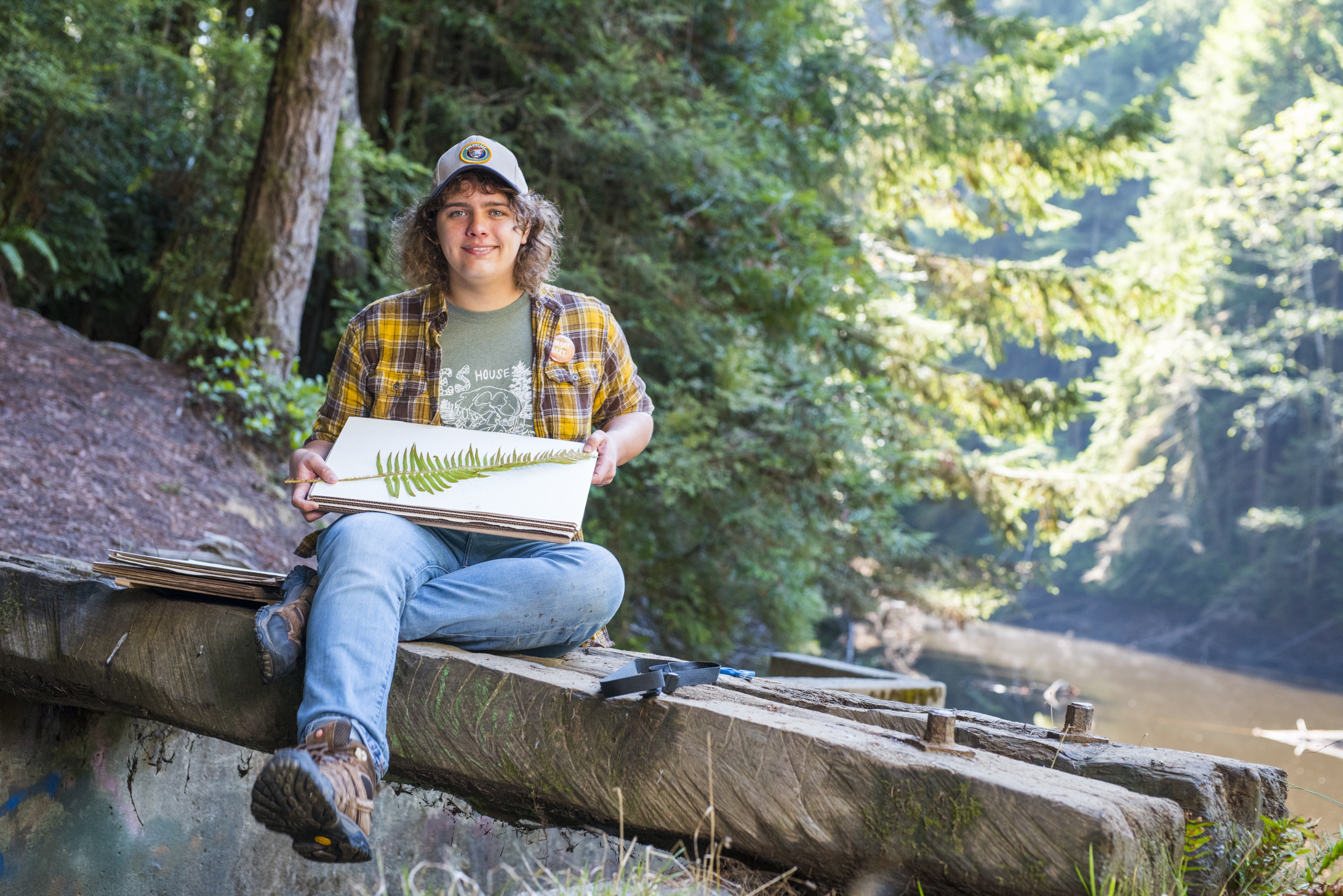 Cal Poly Humboldt student sitting in forest collecting fern sample.
