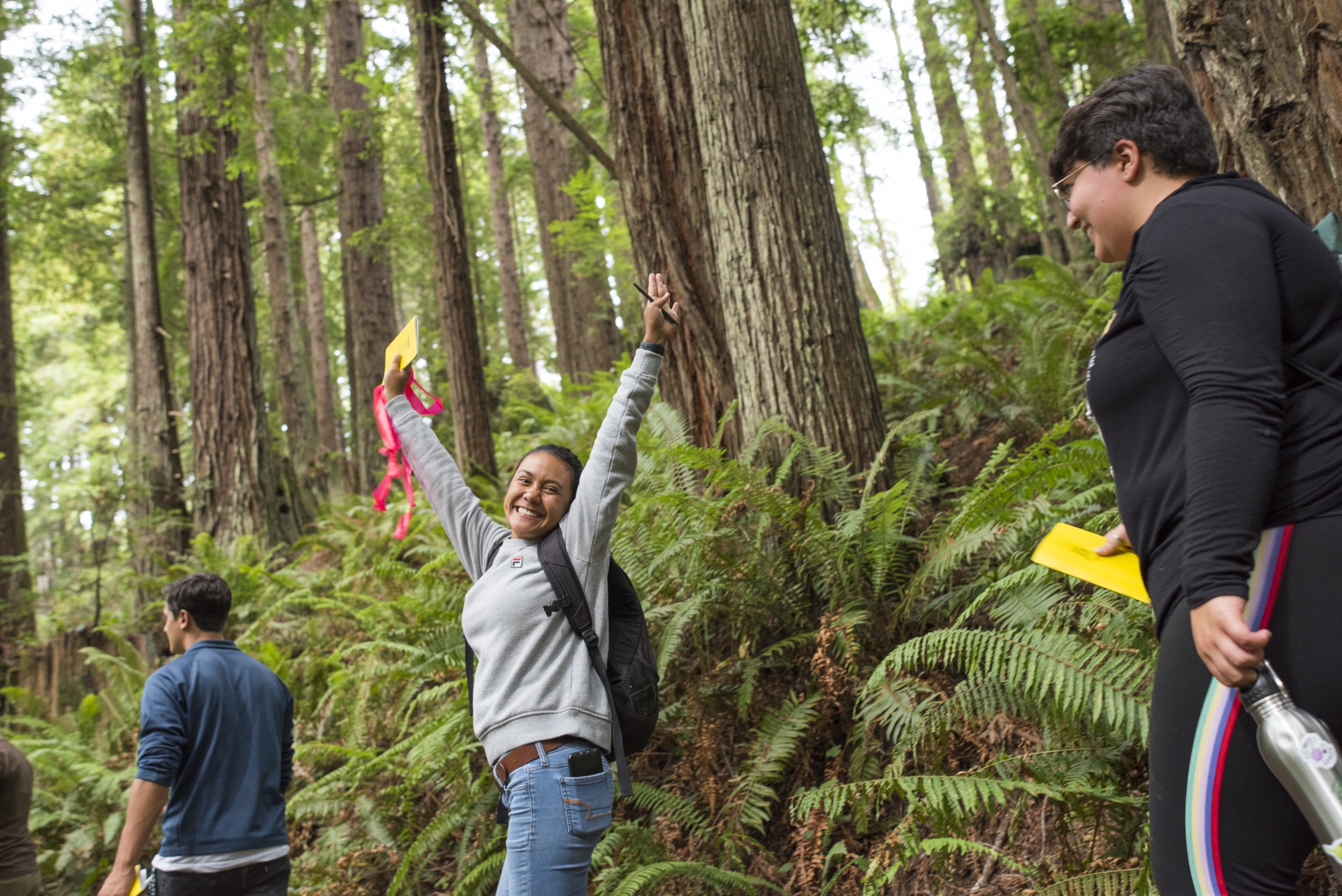 Cal Poly Humboldt student in the forest raising hands in celebration.