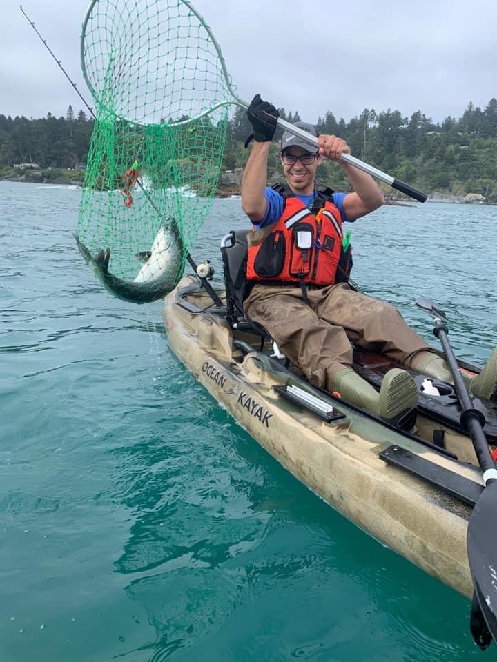 Nicholas Brunner catches a fish in a net from a kayak